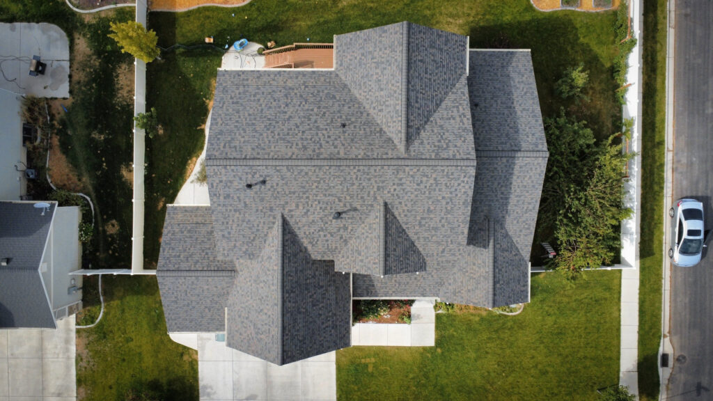 Roofing Contractor in Charleston - UT inspecting shingle wear on a farmhouse roof in morning light