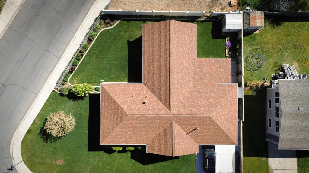 Roof repair specialist in Clearfield - UT inspecting worn flashing and shingle damage on a sloped roof