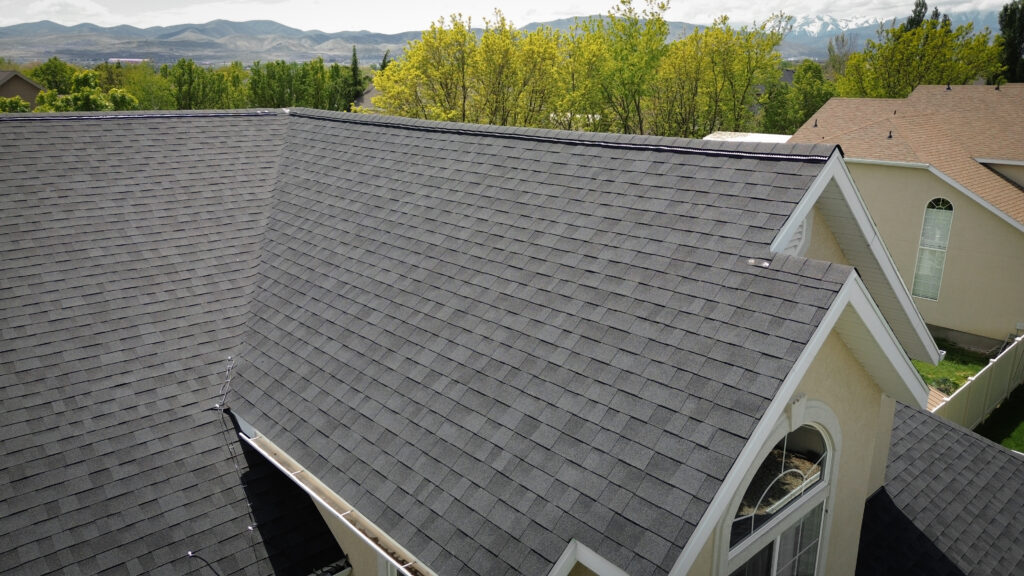 Roofing Contractor in Daniel - UT measuring roof sections beside a rural home at sunrise