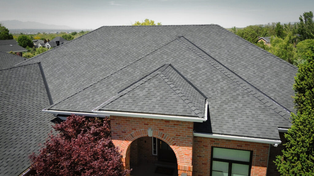 Roofing Contractor in Clearfield - UT checking shingle wear along a residential roof edge