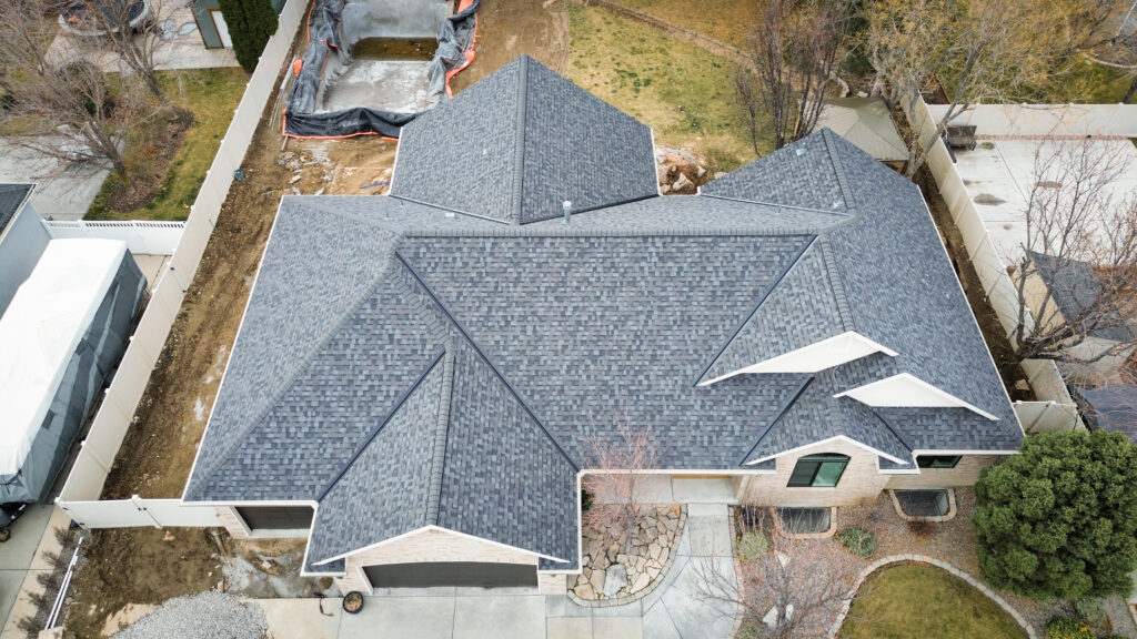 Roofing Contractor in Bountiful - UT inspecting worn shingles beside a roof vent
